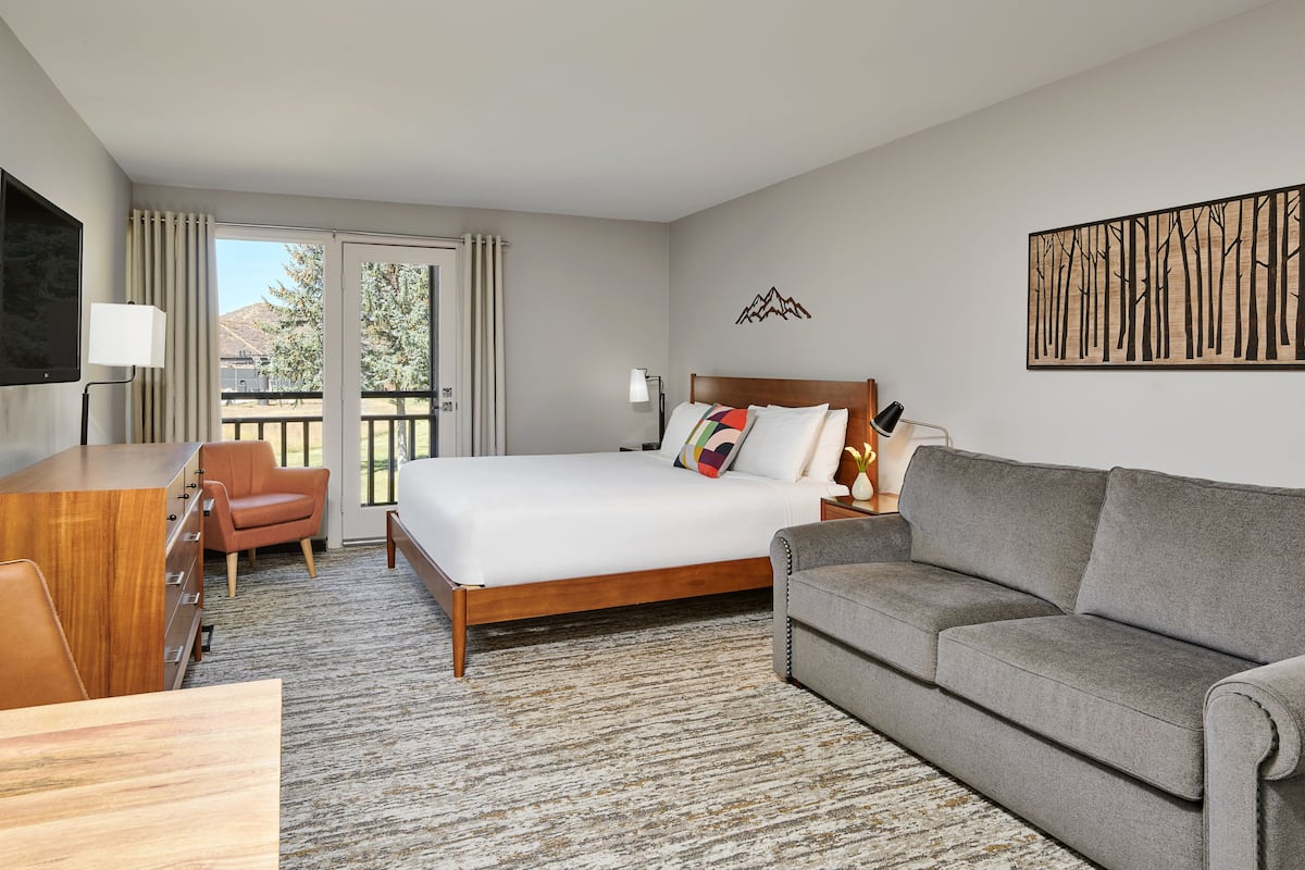 A hotel room with a bed, a sofa, a desk, and a TV.
