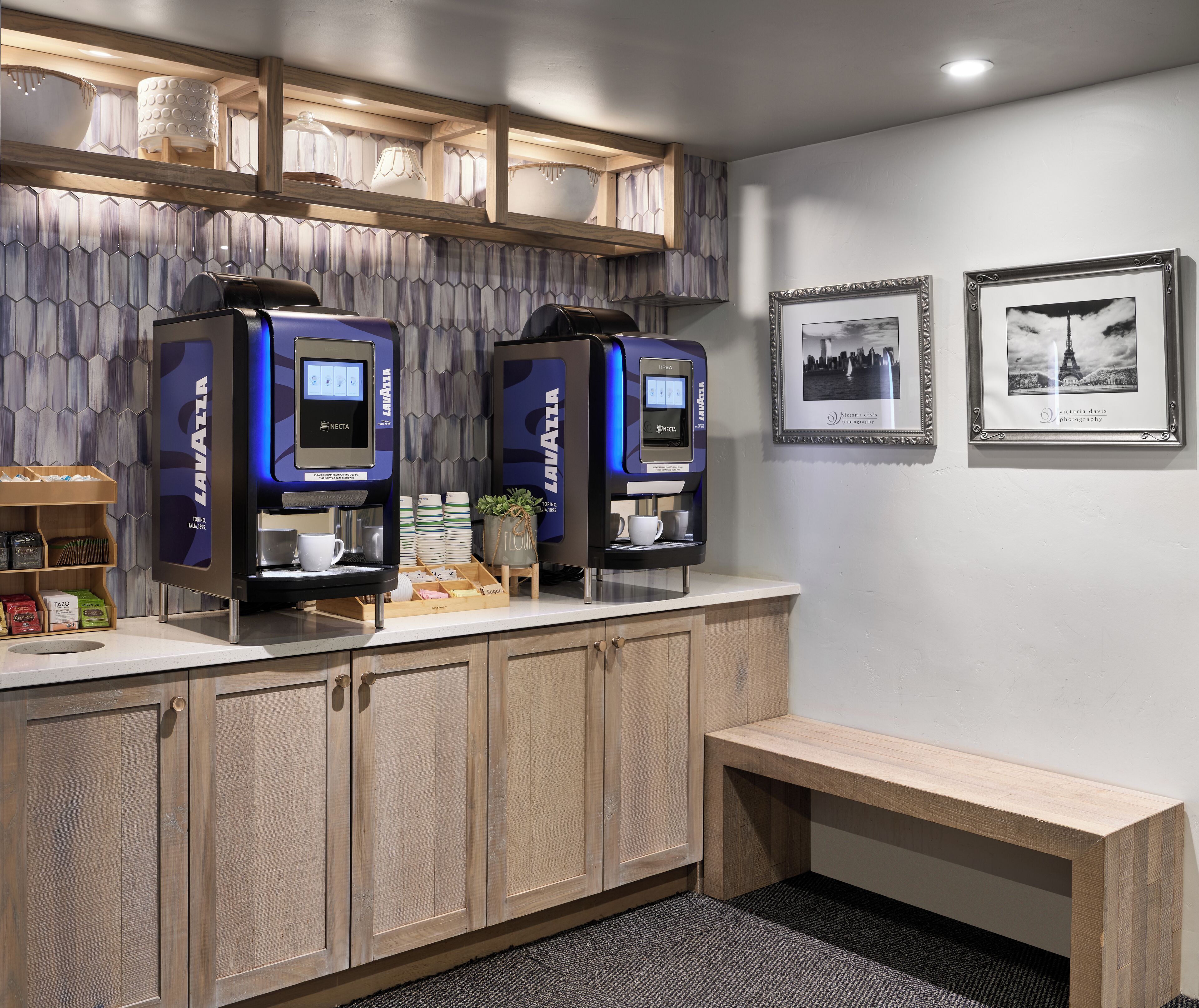 A modern coffee station with two Nespresso machines, a small plant, and a coffee display.