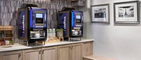 A modern coffee station with two Nespresso machines, a small plant, and a coffee display.