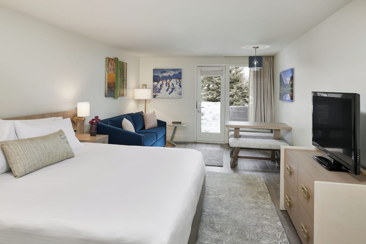A hotel room with a bed, a sofa, a TV, and a desk.