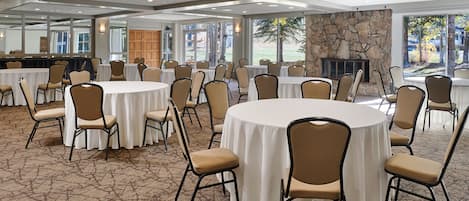 A conference room with round tables, chairs, and a stone fireplace.