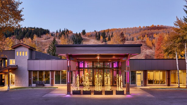 Un bâtiment moderne doté d’un porche, de grandes fenêtres et offrant une vue sur un paysage vallonné.
