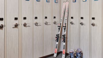 A row of lockers with numbered labels, some with skis and boots placed inside.