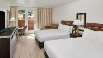 A hotel room with two beds, a desk, a chair, and a television.