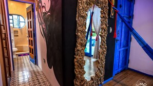 A hallway with a patterned floor, a mirror with a crinkled frame, and a blue door.