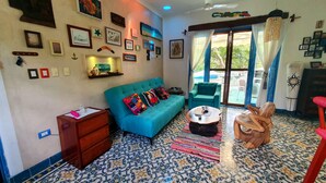 A cozy living room with a blue sofa, a wooden side table, and a patterned floor.