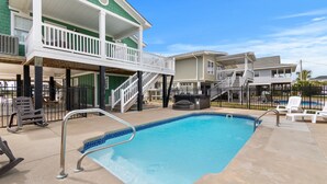 A swimming pool with a deck area, lounge chairs, and a building with a balcony. - 3BR w/ Private Pool and Hot Tub in Garden City Beach (Garden City Beach)