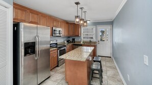 A modern kitchen with stainless steel appliances, wooden cabinets, and a granite countertop. - 3BR w/ Private Pool and Hot Tub in Garden City Beach (Garden City Beach)