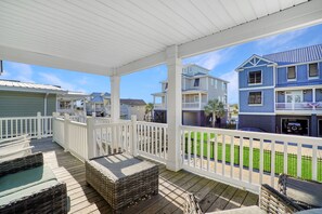 A covered deck with wicker furniture and a white railing, overlooking a residential area with houses and a green lawn. - 3BR w/ Private Pool and Hot Tub in Garden City Beach (Garden City Beach)