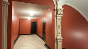 Un pasillo con paredes rojas, columnas blancas y un accesorio de iluminación en el techo.