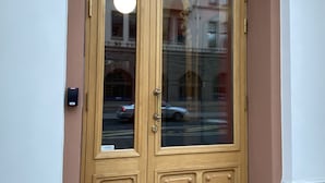 Una puerta doble de madera con un panel de vidrio, una placa con la inscripción "1898" y un pequeño letrero debajo de la puerta.
