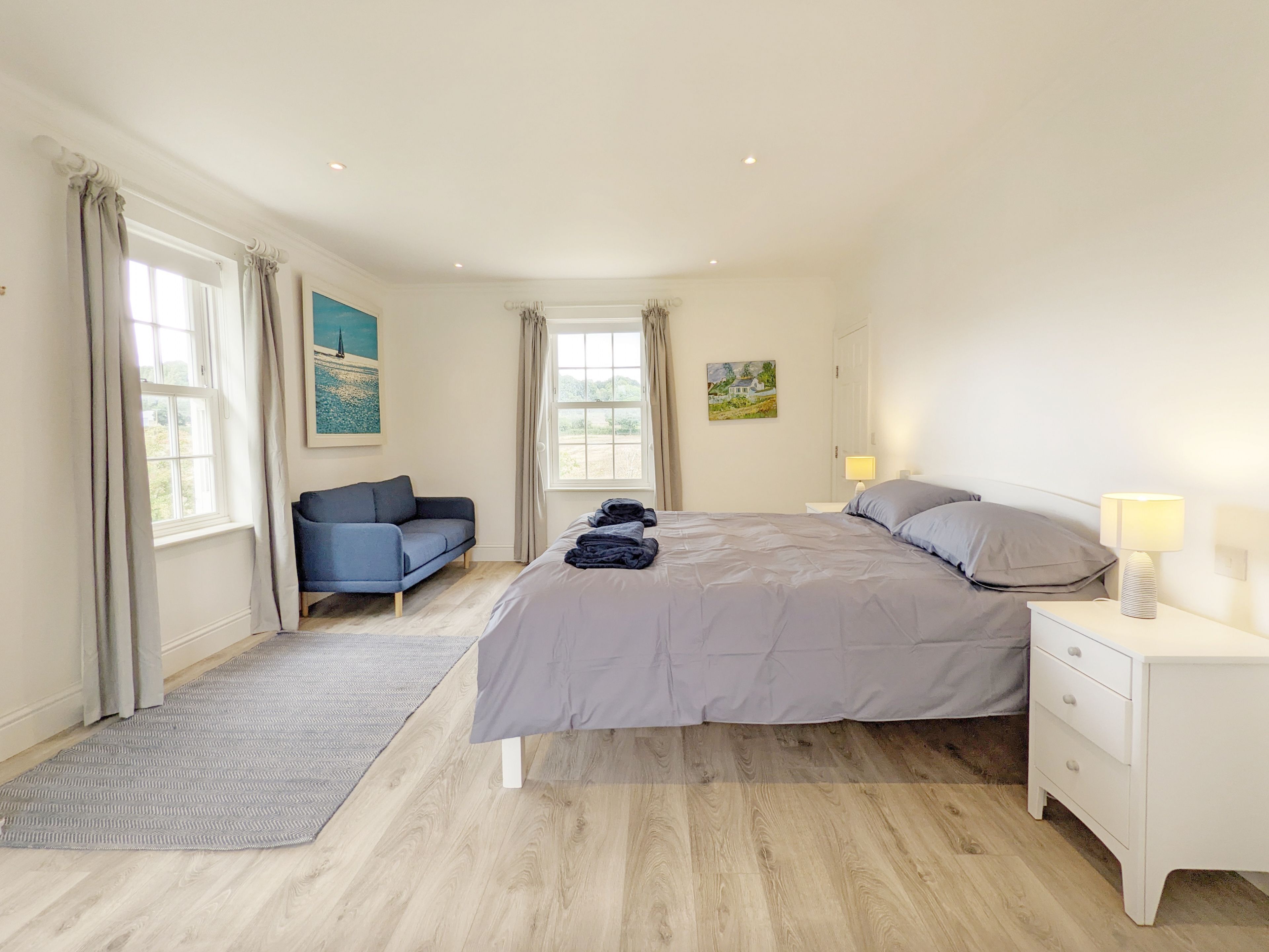 Une chambre à coucher avec un lit, une table de chevet, une lampe, un canapé et un tapis.