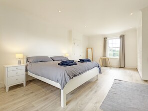 A modern bedroom with a large bed, bedside tables, a small table, and a window with curtains. - The White House - Bordon  - sleeps 10 guests  in 5 bedrooms (Bordon)