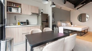 A compact kitchen with modern appliances, a dining area with a table and chairs, and a bed with a headboard. - w* | Splendid Loft with Terrace near Polanco (Ciudad de México)
