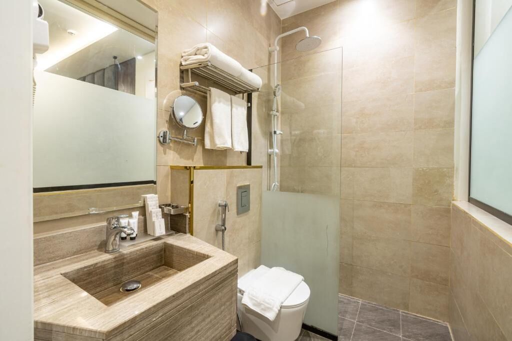 Une salle de bain moderne avec un lavabo en marbre, une douche à parois de verre et des toilettes.