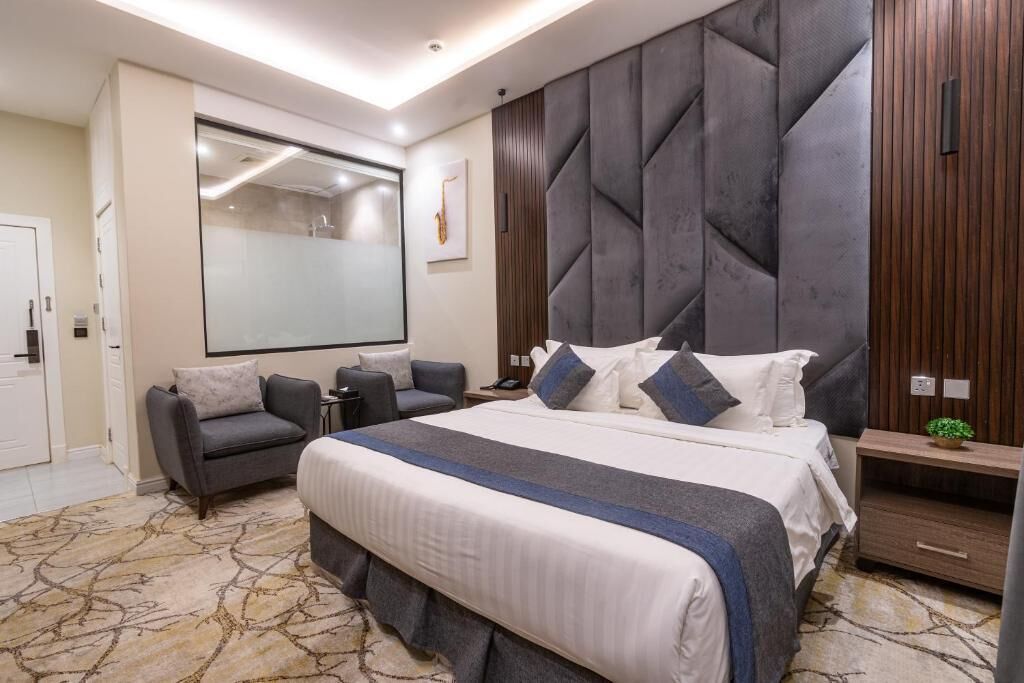 Une chambre moderne avec un grand lit, un canapé, un bureau et un grand miroir.