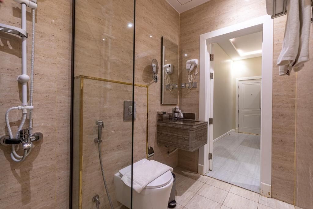 Une salle de bain moderne avec une douche à parois de verre, des toilettes blanches, un meuble-lavabo avec un miroir et un porte-serviettes.