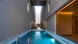 En inomhuspool med fri sikt upp mot taket och väggarna, omgiven av ett kaklat golv och ett träpanelat tak.