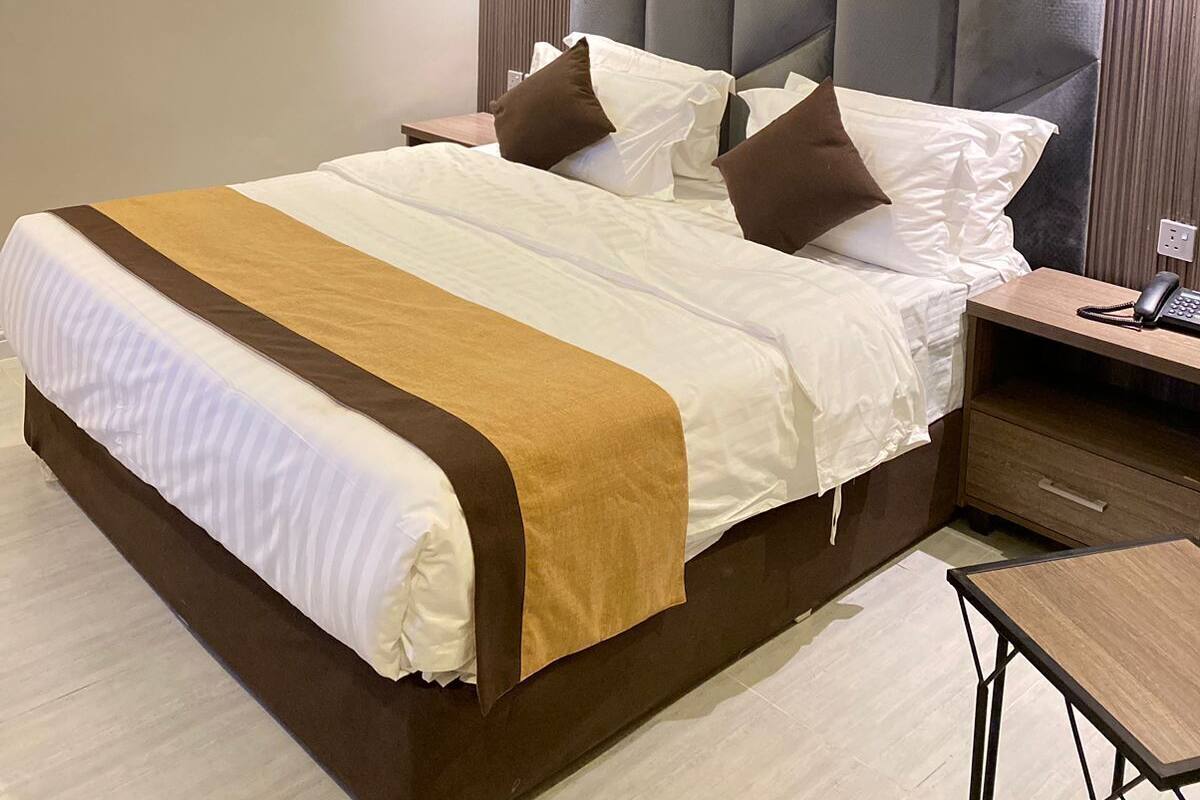 Moderni hotellihuone, jossa on suuri sänky, puinen yöpöytä ja pieni pöytä.