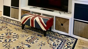 Un salon avec un téléviseur à écran plat posé sur un meuble de télévision blanc, un tapis à motifs et une ramure de cerf décorative accrochée au mur.