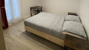 Un dormitorio con cama, una mesita, una silla y una lámpara en el techo.