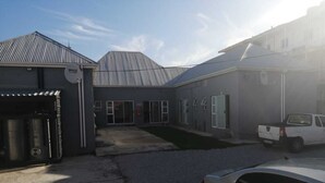 A building with a garage, a covered driveway, and a parked white pickup truck. - monument pavilion (Gqeberha (Port Elizabeth))
