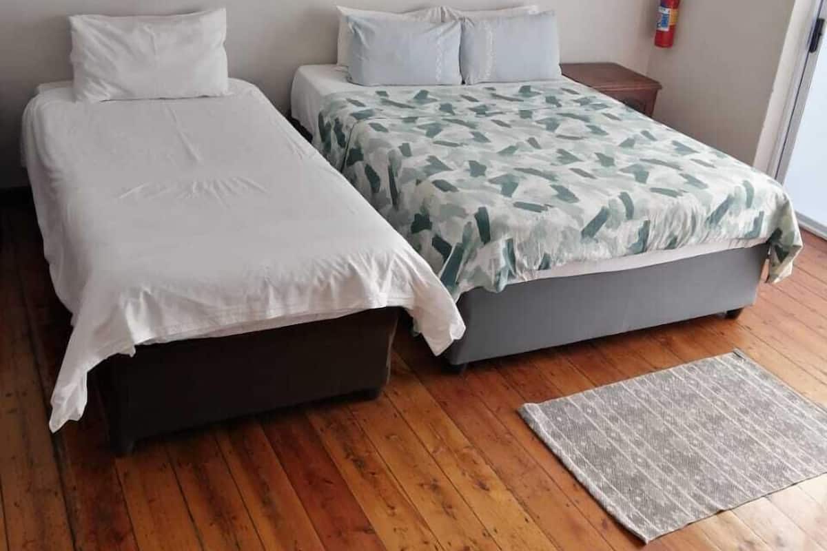 Ein Zimmer mit zwei Betten, Holzboden und einem Feuerlöscher an der Wand.
