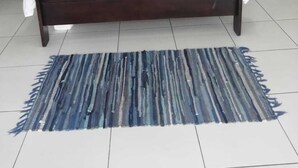 A bedroom with a dark wooden bed, white pillows, two bedside tables, and a blue striped rug. - monument pavilion (Gqeberha (Port Elizabeth))