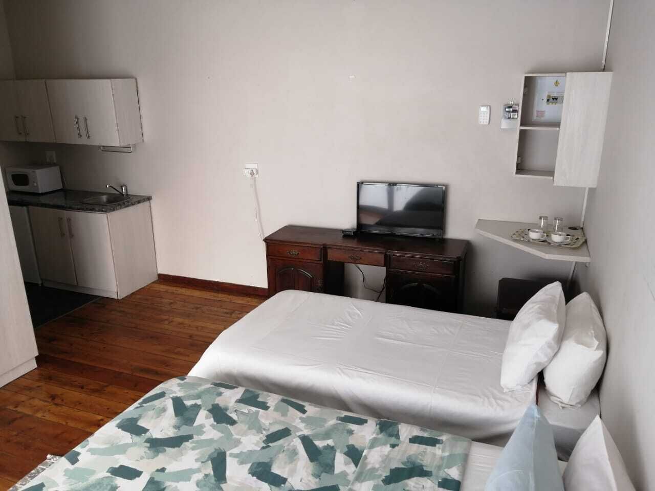 Une chambre d’hôtel de taille réduite, comprenant un lit, un bureau, une télévision et une petite kitchenette.