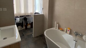 Un bagno moderno con una vasca da bagno indipendente, un mobile contenitore in legno e una cabina doccia.