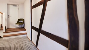Ein Flur mit einer Holztreppe, die zu einer Tür führt, einem Stuhl und einem gemusterten Boden.