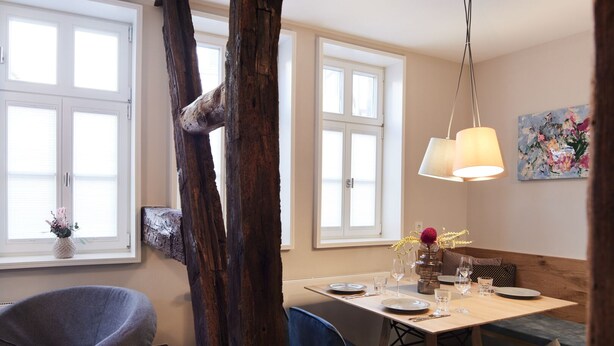 Ein Essbereich mit Holztisch, Stühlen und einer Hängelampe.