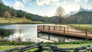 A wooden bridge over a calm lake with a forested hill in the background. - EpicViews!~EasyRoads!~HotTub~FirePlace~Firepit (Sevierville)