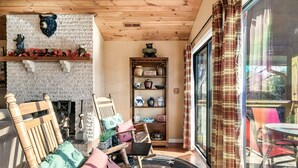A cozy room with a fireplace, wooden chairs, a rug, and a glass door leading to an outdoor area. - EpicViews!~EasyRoads!~HotTub~FirePlace~Firepit (Sevierville)