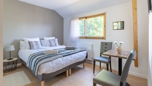 Een slaapkamer met een bed, nachtkastje, stoel en een raam met gordijnen.