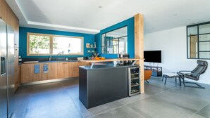 Una cocina moderna con una isla central, armarios de madera y un ventanal amplio.