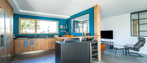 Une cuisine moderne dotée d’un îlot central, de meubles en bois et d’une grande fenêtre.