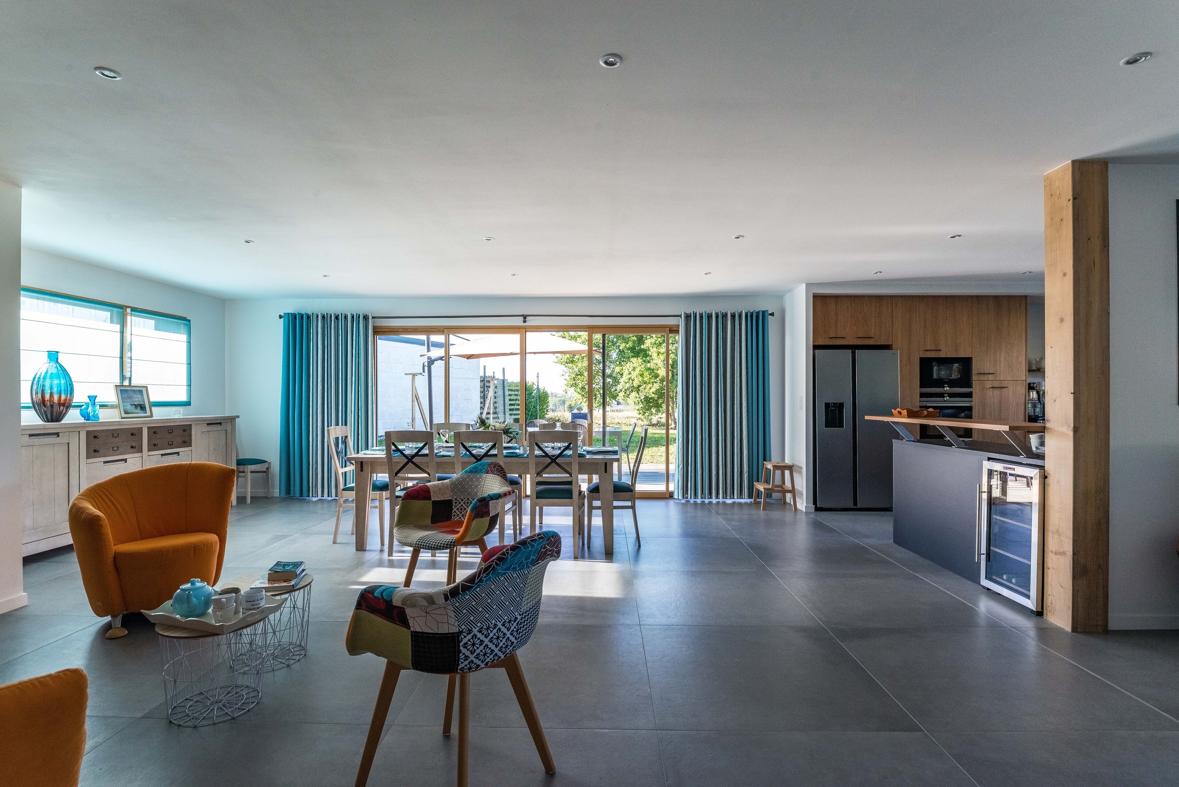 A spacious living area with a dining table, chairs, and a kitchen area with modern appliances.