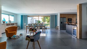 Amplia sala de estar con mesa de comedor, sillas y zona de cocina equipada con electrodomésticos modernos.