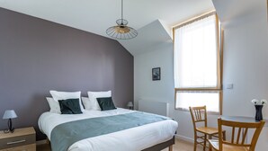 Un dormitorio con cama, mesita de noche, lámpara y ventana con cortinas.