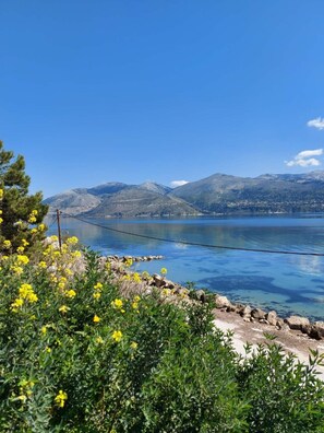 A coastal landscape with a clear view of a lake, mountains in the background, and a bridge in the distance. - Apollonides Seafront Villa 1 “Aoede” (Kefalonia)