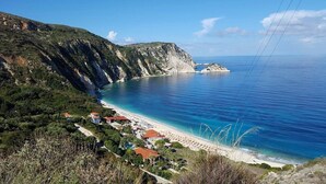 A coastal area with a beach, a cliff, and a small island. - Apollonides Seafront Villa 1 “Aoede” (Kefalonia)