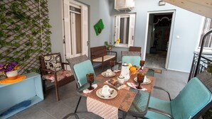A dining area with a table set for four, surrounded by chairs, and a decorative wall with plants. - Sea View Nikos Apartment (Ναύπλιο)