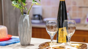 A kitchen counter with a vase of red roses, a bottle of wine, and two glasses. - Sea View Nikos Apartment (Ναύπλιο)