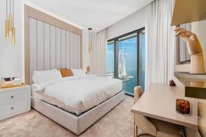 Una habitación de hotel moderna con una cama grande, un escritorio y vistas a un paisaje urbano a través de ventanales de gran altura.