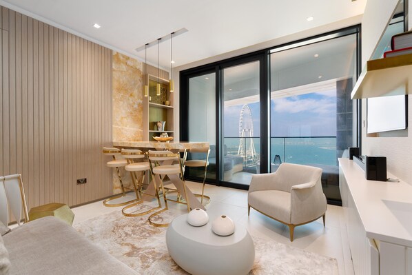 Una sala de estar moderna con comedor, un ventanal con vistas a la ciudad y un balcón con vistas al agua.
