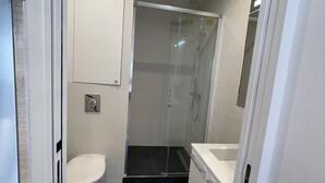 Un baño moderno con inodoro, cabina de ducha y tocador.