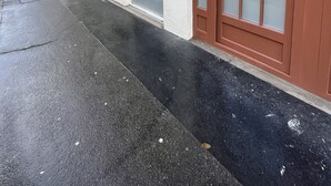 Un edificio con un amplio portón de garaje, una ventana con diseño de cuadrícula y una puerta con paneles de vidrio esmerilado.