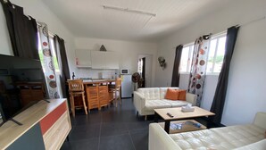 Un espace de vie compact comprenant un coin cuisine, un canapé, une table à manger et un téléviseur.