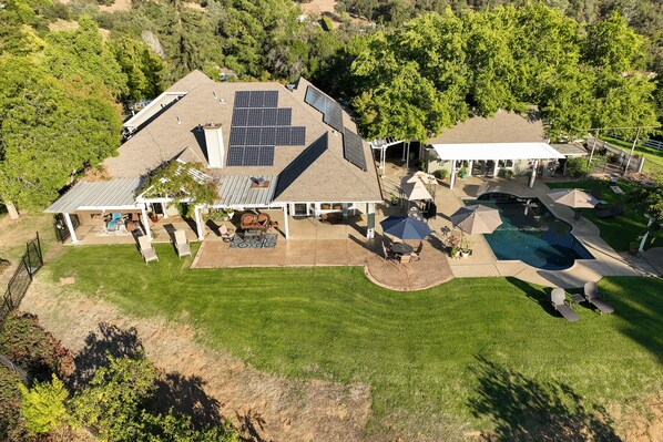 Una casa con techo solar, piscina y patio cubierto.